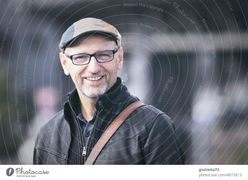 Portrait of happy, cheerful man with glasses, cap and gray three-day beard | UT HH19 portrait Central perspective Shallow depth of field blurriness Day