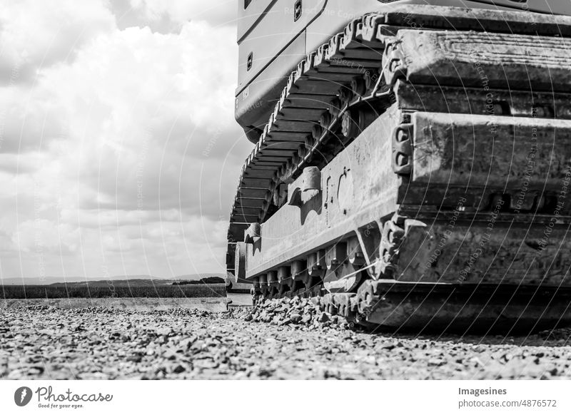 Excavator - caterpillar. Black and white close up of excavator on construction site. Excavating machines on construction site on cloudy sky background