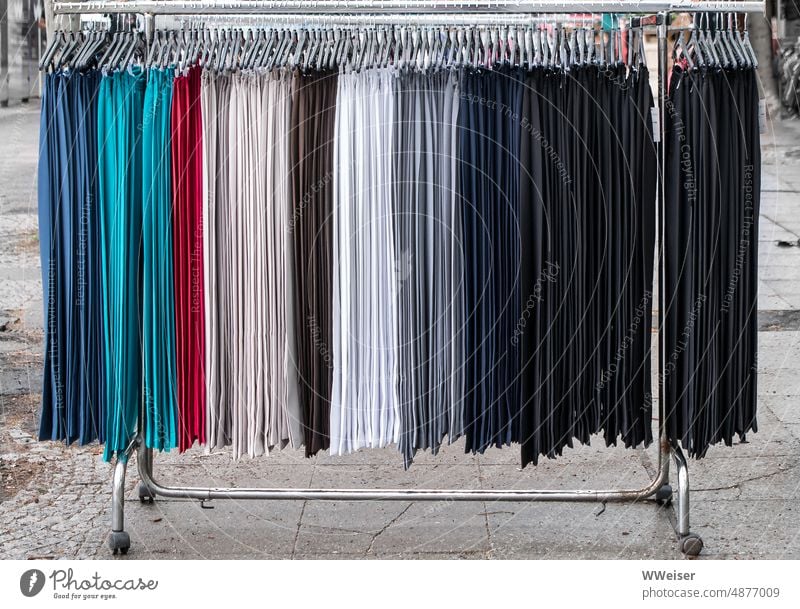 On the bar at the weekly market hang uniform pants of different colors Trousers garments Markets Farmer's market Sell Offer pole Off-the-rack hangers variegated