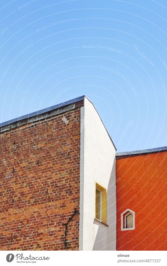 two adjoining houses of brick construction, partly plastered, painted white and orange with two windows Apartment Building Brick building Brick construction