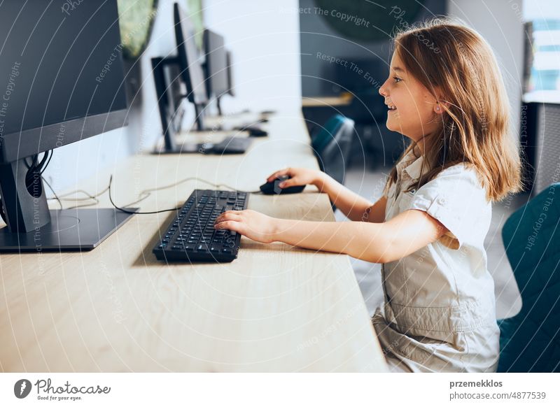 Child learning to use technology in classroom at primary school. Schoolgirl using computer on elementary computer science class. Back to school schoolgirl child