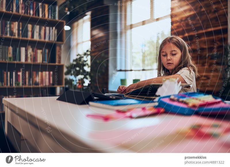 Schoolgirl learning, playing, doing puzzles and reading book in school library. Primary school pupil is engaged in book with jigsaw. Child curiosity back