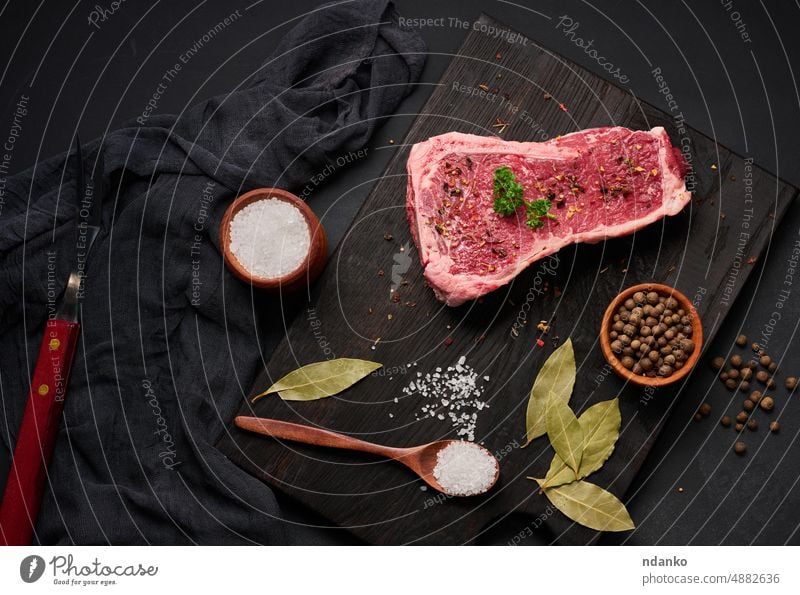 Fresh raw piece of beef meat, striploin steak on a black background, top view. Marbled piece of meat bone barbecue bbq beefsteak board butcher chop cuisine cut