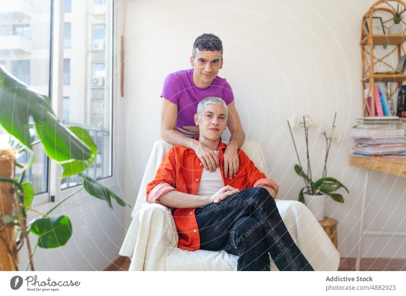 Smiling Gay Couple Sitting On Armchair At Home Love Embrace Arm Around Makeup Fashion Happy Portrait Together Bonding Queer Pride Individuality Lifestyle