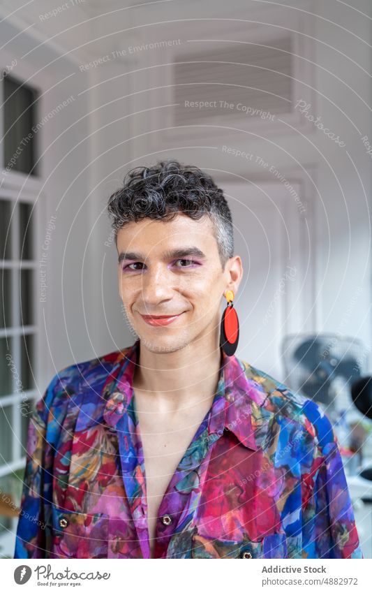 Confident Transgender Man In Casual Sitting On Sideboard Portrait Gay Lifestyle Home Shirt Happy Earring Androgynous Trendy Fashion Looking At Camera Pride