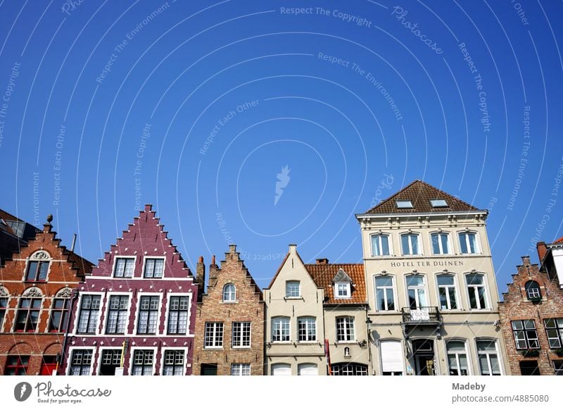 Magnificent colorful restored facades of old houses on the canal against blue sky in the sunshine in the old town of Bruges in West Flanders in Belgium