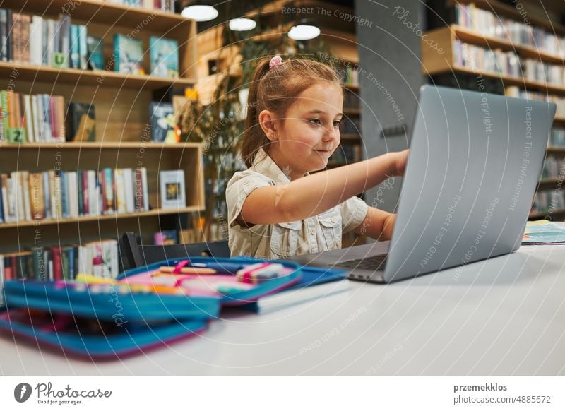 Engaged student doing her homework using laptop in after school club at primary school. Back to school. Child using technology on computer science class. Smart girl learning from educational application at school