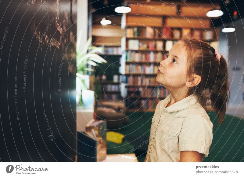 Little girl writing on blackboard. Smart student put solve on chalkboard. Back to school. Child having class. Schoolgirl learning at primary school back child