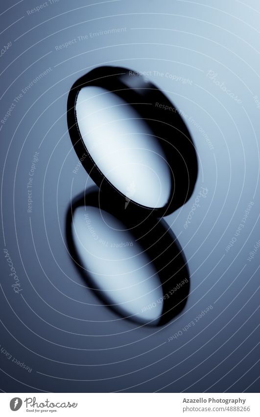 Minimal still life image of a round object on shiny surface in blue monochrome. close up macro minimalism standing rolling motion moving creative simplicity