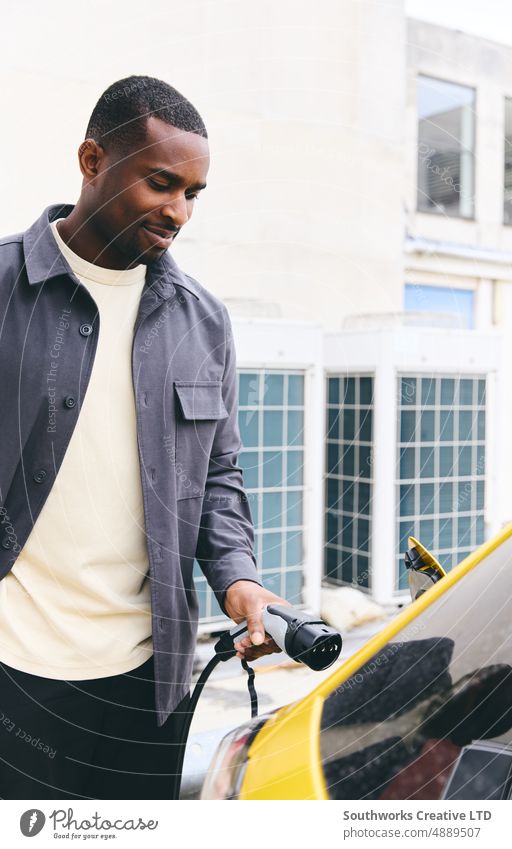 Man Plugging In Electric Car Outside Office In Car Park Charging EV charging African american hand Connecting businessman Black outside office work car park