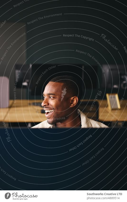 Young black man working on computer in modern office at desk professional businessman internet technology adult smiling male workplace creative black ethnicity