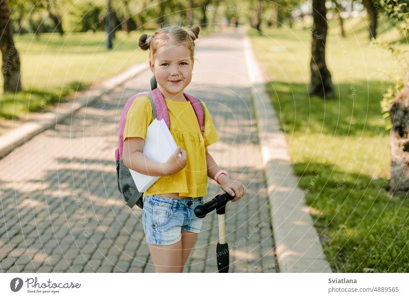 A beautiful little girl rides a scooter on her way back to school child riding education schoolchild schoolbag backpack street balance suburbs outdoors