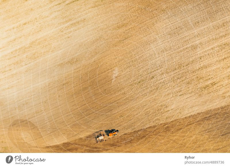 Aerial View. Tractor With Seed Drill Machine Sowing The Seeds For Crops In Spring Season. Beginning Of Agricultural Spring Season. Countryside Field Landscape. Natural Rural Background