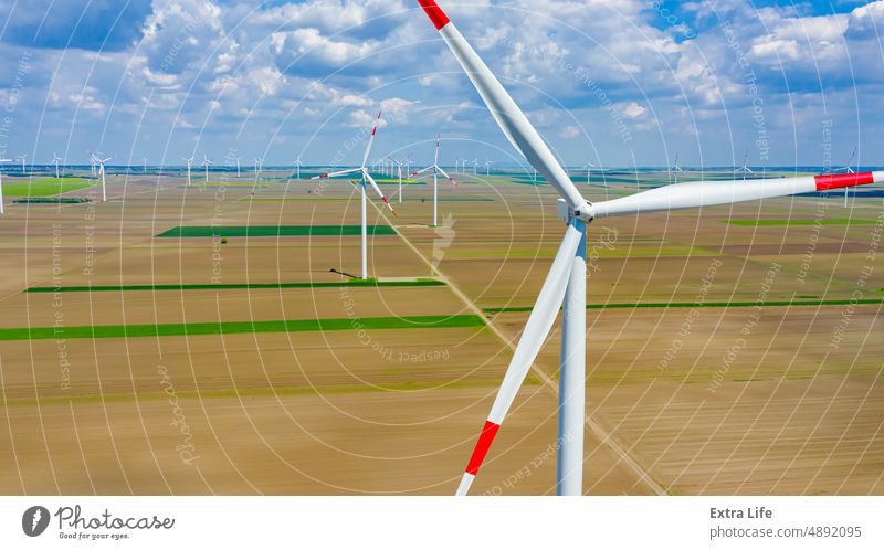 Aerial view of several windmills, wind generators, turbines, producing renewable clean energy by converting kinetic energy Above Agricultural Agriculture