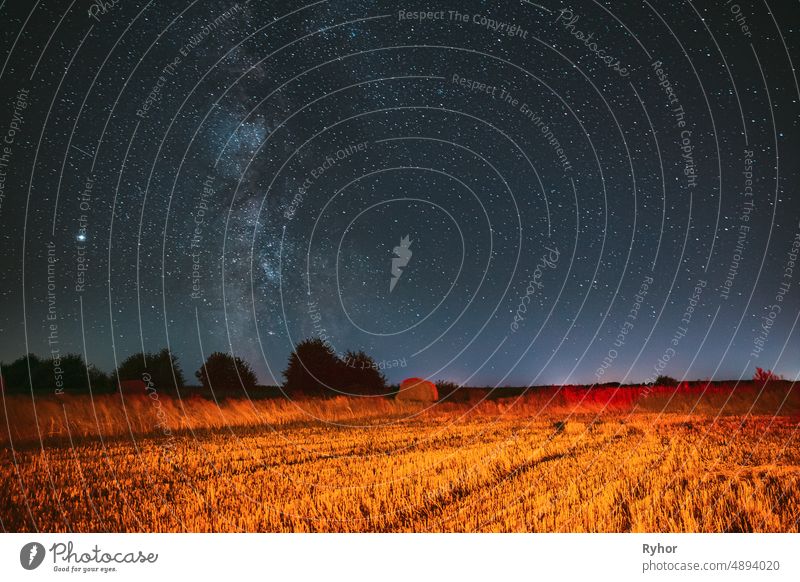 Milky Way Galaxy In Night Starry Sky Above Haystack In Summer Agricultural Field. Night Stars Above Rural Landscape With Hay Bale After Harvest. Agricultural Concept