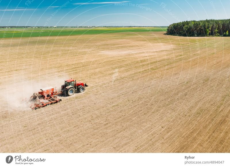 Aerial View. Tractor With Seed Drill Machine Sowing The Seeds For Crops In Spring Season. Beginning Of Agricultural Spring Season. Countryside Rural Field Landscape