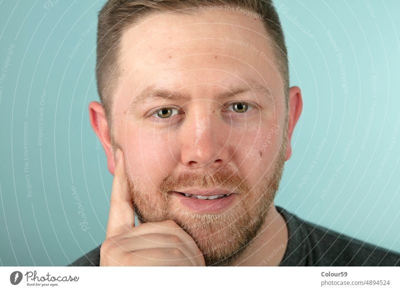 Bearded casual man looking pensively at the camera portrait studio shot copy space looking at camera young unshaven handsome confident smiling hope positive