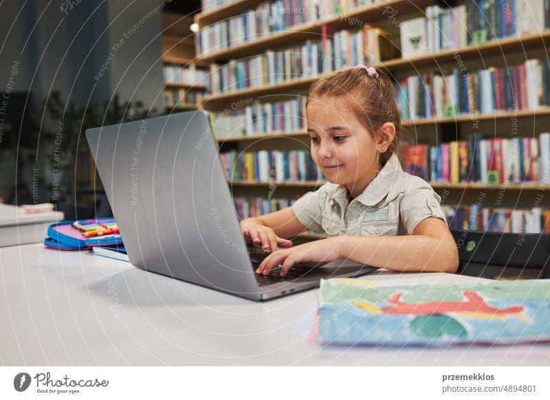 Engaged student doing her homework using laptop in after school club at primary school. Back to school. Child using technology on computer science class. Smart girl learning from educational application at school