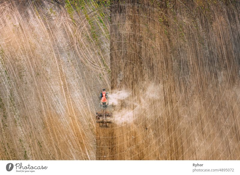 Aerial Flat View. Tractor Plowing Field In Spring Season. Beginning Of Agricultural Spring Season. Cultivator Pulled By A Tractor In Countryside Rural Field Landscape