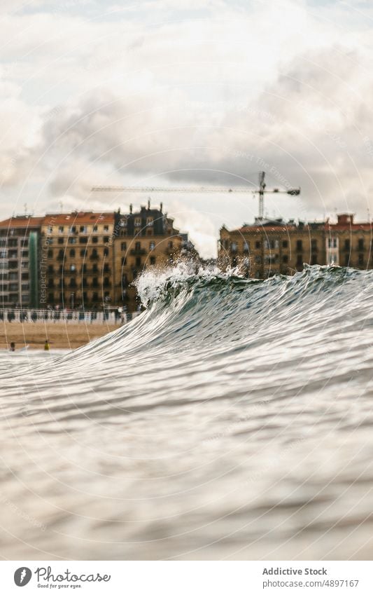 Stormy blue sea with waves near buildings ocean power water nature landscape seascape coast surf crest summer splash foam seashore surface storm wet adventure