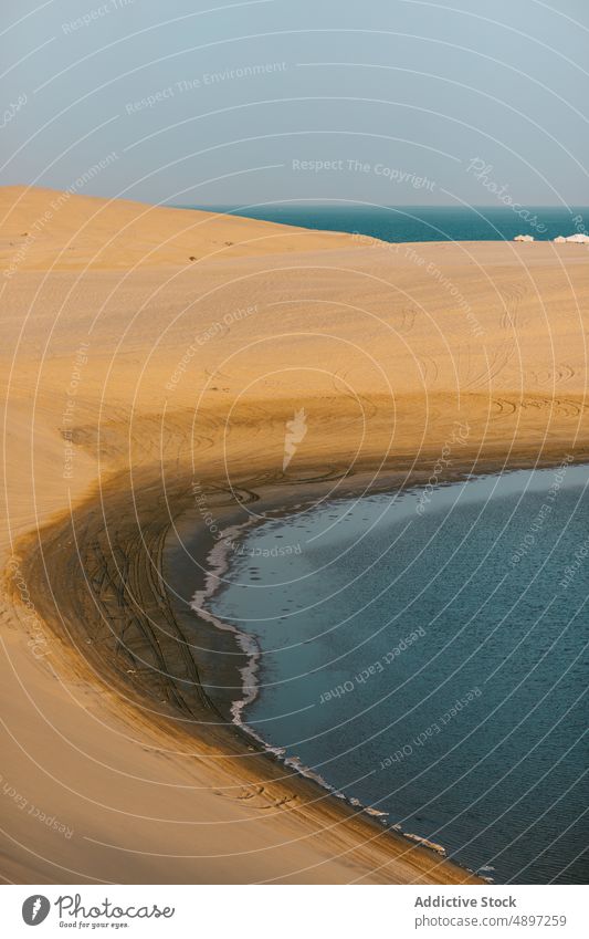 Sandy desolate beach near sea dune sand summer desert blue sky dry seaside landscape doha qatar coast shore water daytime peaceful drought hot scenery barren