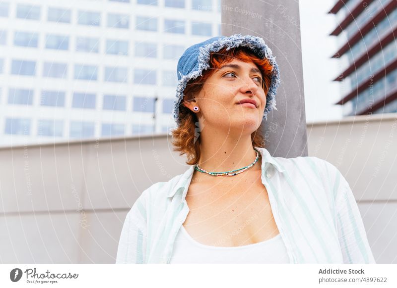 Smiling woman with hat near wall hobby pastime leisure street urban content smile activity enjoy cheerful wear casual building attractive summertime city female