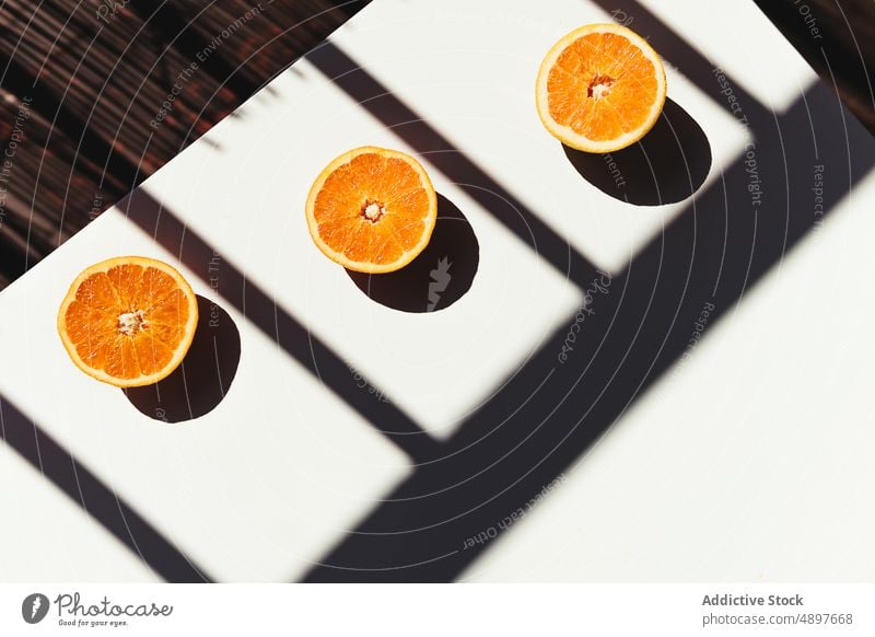 Halves of squeezed oranges on sunlit table composition morning juice diet shadow railing fresh sunlight half vitamin fruit citrus ripe organic sweet breakfast