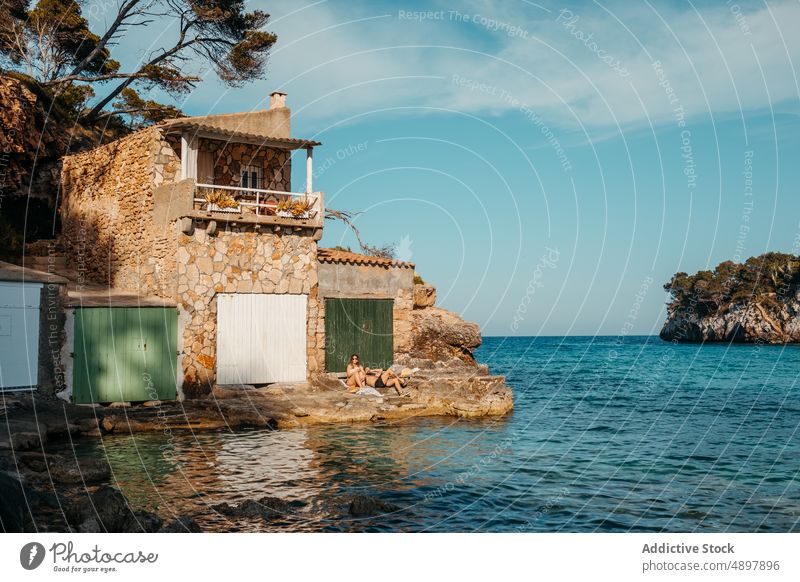 Anonymous tourists sunbathing on rocky seashore in Mallorca couple relax holiday together rest house travel seacoast vacation mallorca balearic islands spain