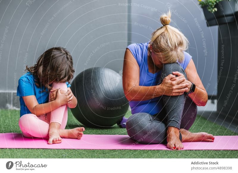 Senior Woman And Girl Practicing Yoga On Exercise Mat Training Relax Family Leg Flexibility Hugging Knee Meditate Teaching Fit Healthy Learning Child Active