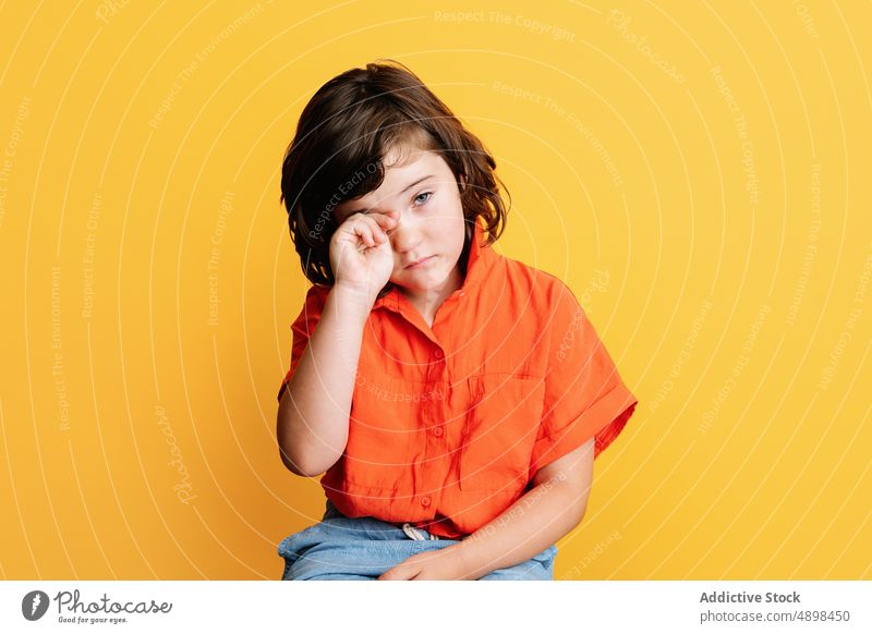 Calm girl in bright shirt calm casual colorful sit unhappy appearance portrait little style kid dark hair upset gray eyes vibrant sad serious brunette isolated