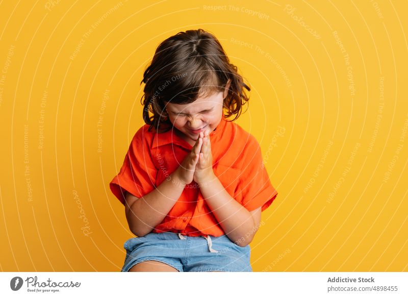 Cheerful girl smiling rubbing hands smile happy style colorful bright child casual portrait delight gesture childhood little glad vibrant joy sincere vivid kid