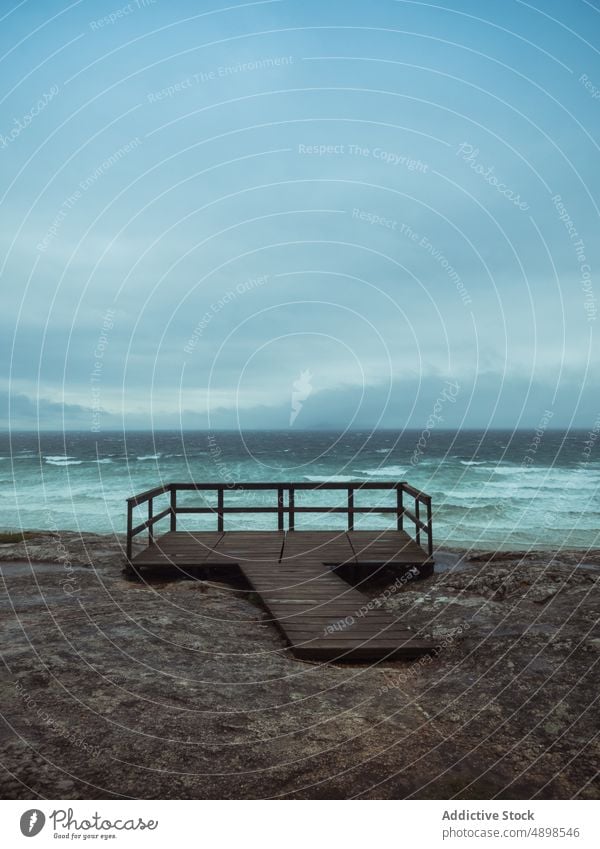 Wooden platform near stormy sea shore boardwalk sky cloudy wave gray viewpoint rias baixas galicia spain seaside ocean rough marine timber dull railing stone