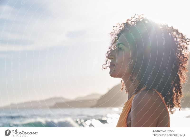 Hispanic woman by the sea on a sunny day street appearance style summer feminine blue sky sunlight enjoy ethnic hispanic cheerful positive female glance glad