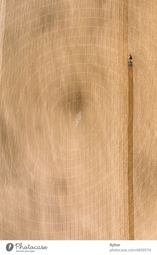 Tractor Plowing Field In Spring. Beginning Of Agricultural Season. Cultivator Pulled By A Tractor In Countryside Rural Field. Countryside Field Landscape. Aerial View. Top Flat View