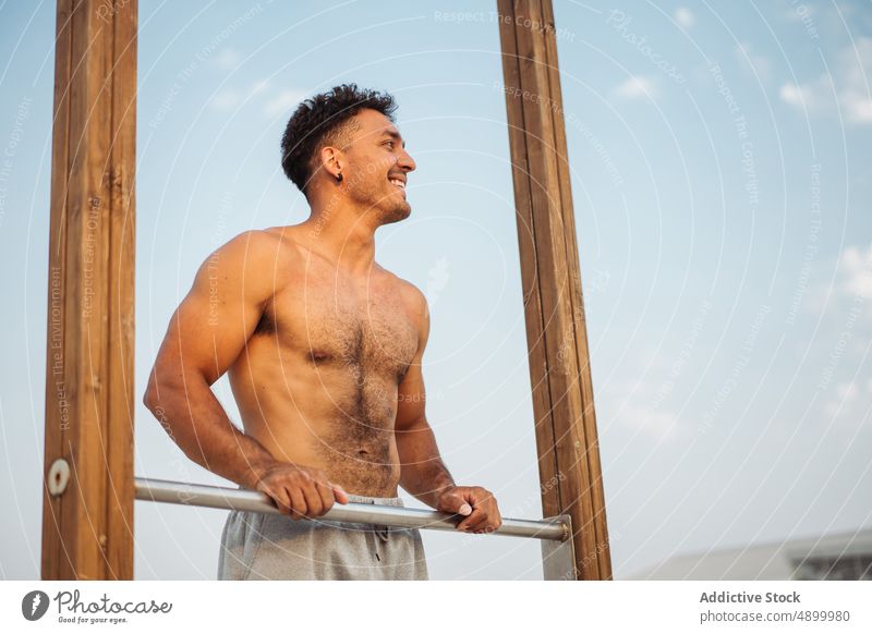 Sportsman standing near bar during calisthenics training sportsman smile hand break hispanic rubbing rest relax prepare happy latin athlete exercise ethnic