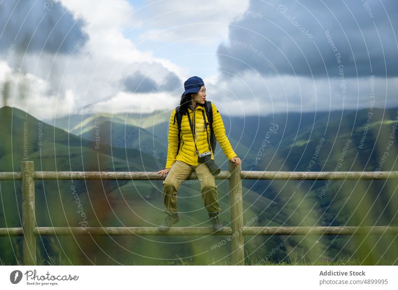 Portrait of beautiful Asian girl sitting on handrail with green Chinese girl Spain active backpack calm camera cap device enjoy europe flowers freedom fun grass