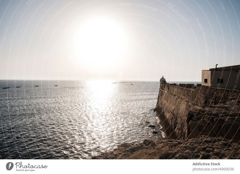 Structure on shore near sea beach water building construction seashore coast nature coastal structure cloudless sky summer rocky sunlight sunshine environment