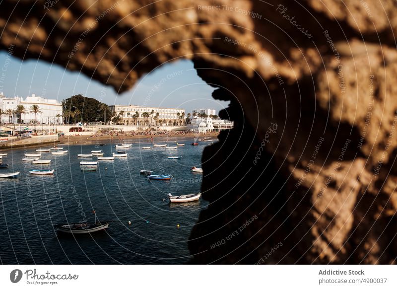 Boats floating near coastal town shore harbor boat vessel port water sea rock seashore building house pier marine transport nautical residential embankment city