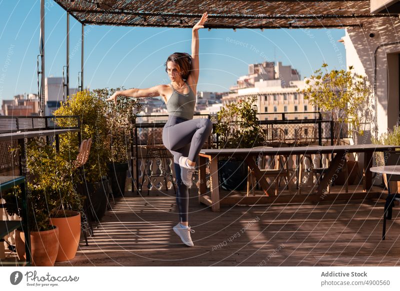 Sportswoman exercising on terrace of building sportswoman exercise training workout sporty healthy lifestyle practice hobby city leg raised arm raised balance