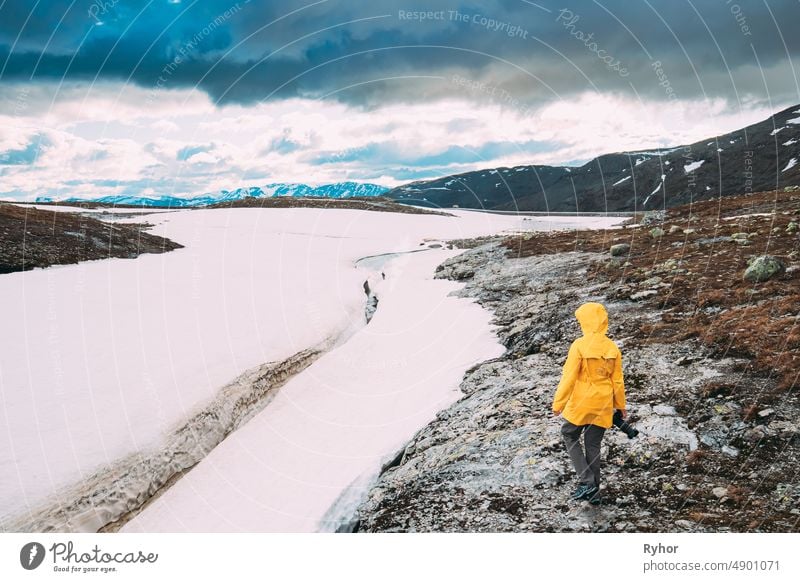 Aurlandsfjellet, Norway. Happy Young Woman Tourist Traveler Photographer With Camera Walking Near Aurlandsfjellet Scenic Route Road. Active Lifestyle In Norwegian Nature