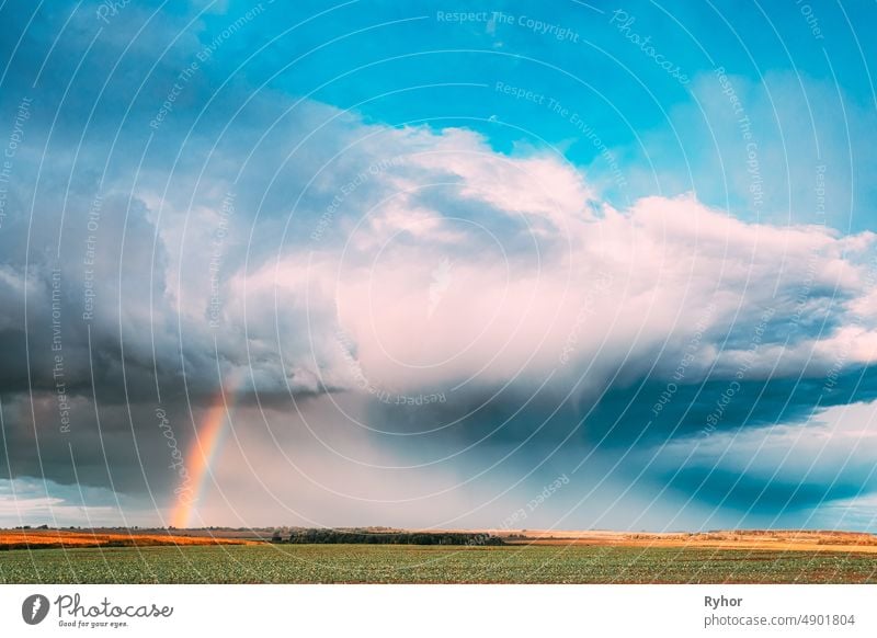 Dramatic Sky During Rain With Rainbow On Horizon Above Rural Landscape Field. Agricultural And Weather Forecast Concept. Countryside Meadow In Autumn Rainy Day