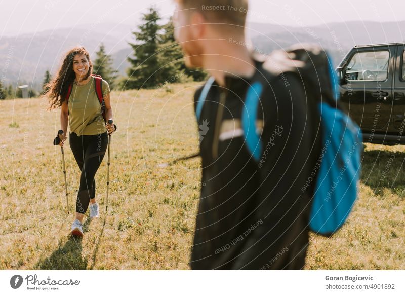 Smiling couple starting walking with backpacks over green hills active activity adults adventure backpacker backpacking boyfriend caucasian countryside curly