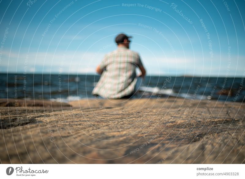 Man sitting on a rock by the sea near Jakobstad/Pietarsaari Rock relaxing tranquillity Summer vacation look relaxed Sit Stone rocky coast Finland Scandinavia