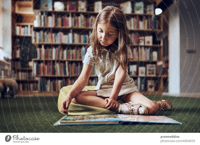 Child solving riddle in book in school library. Primary school pupil is involved in book with riddles. Smart girl learning to solve problems. Benefits of everyday practice