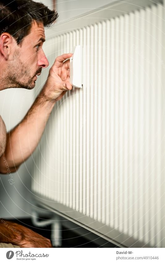 Man reads the consumption of a heating system at a heat meter and looks shocked Heating thermostat heating costs Cooking oil Gas Expensive Prices