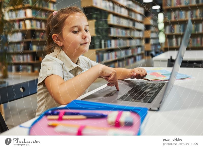 Engaged student doing her homework using laptop in after school club at primary school. Back to school. Child using technology on computer science class. Smart girl learning from educational application at school