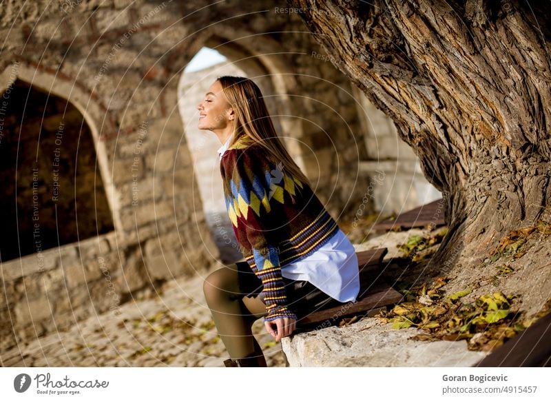 Young woman sitting on the bench watching yellow leaves tree in the autumn park nature female girl person young relax lifestyle outdoor beauty beautiful rest