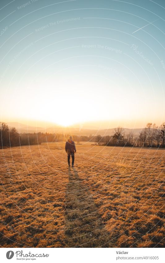 Young ambitious tourist walks through the grain fields at sunset in the Beskydy Mountains, Czech Republic. Reflecting on himself. A walk in the fresh air effect