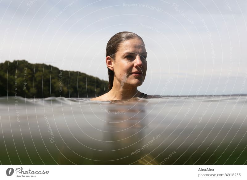 Young beautiful woman in the shallow water in the Baltic Sea looks to the side Lifestyle Back-light salubriously pretty Woman Athletic Slim Esthetic teen