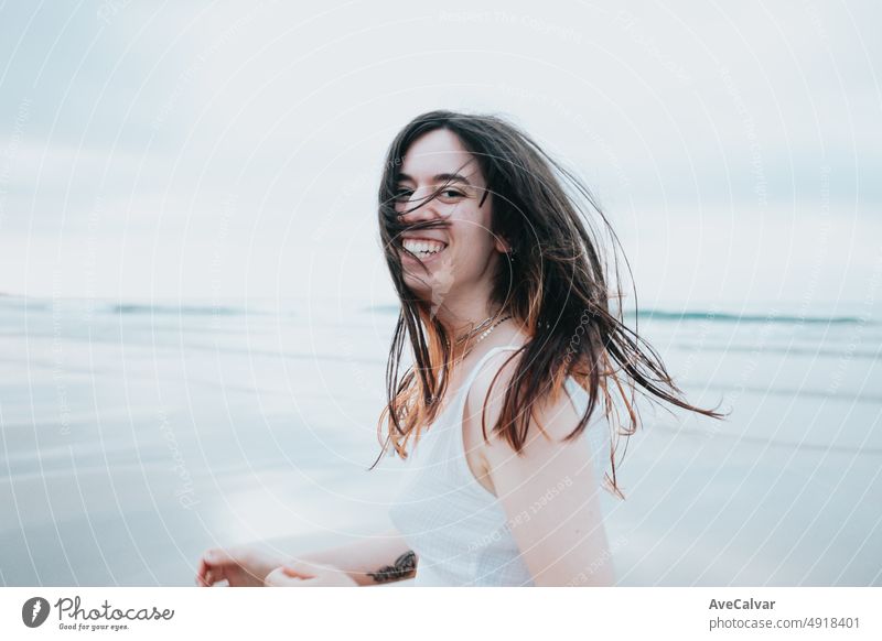 Young woman running on a paradise beach while turning around and smiling to camera carefree. Freedom, liberty and road travel concept. Gen Z modern life, social network, sharing experiences